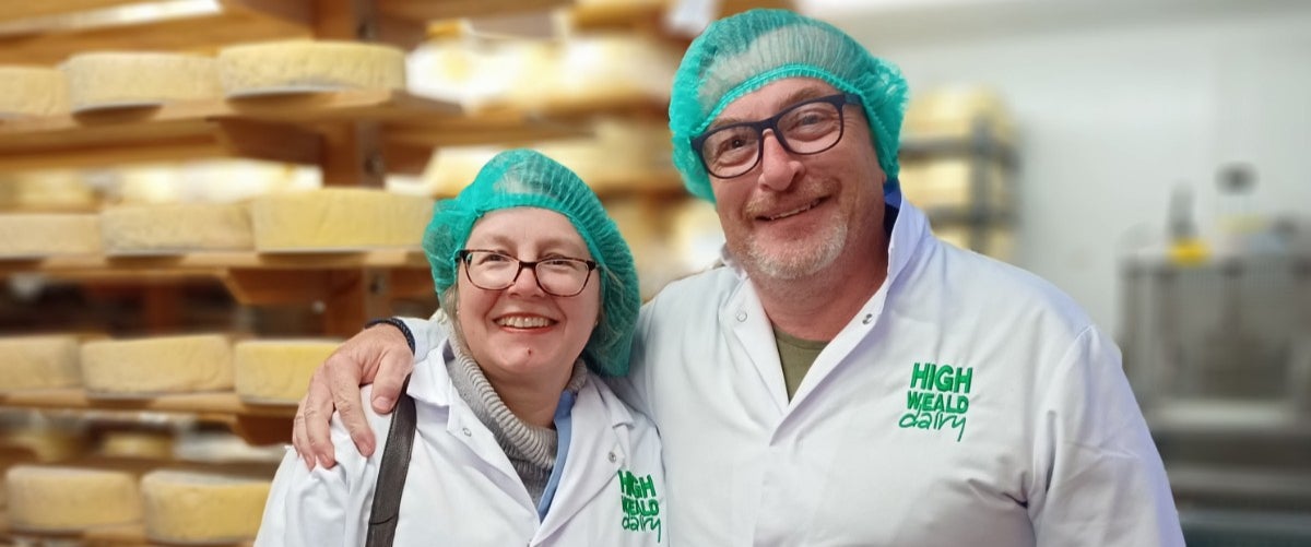 Two adults smiling among the cheese racks at High Weald Dairy